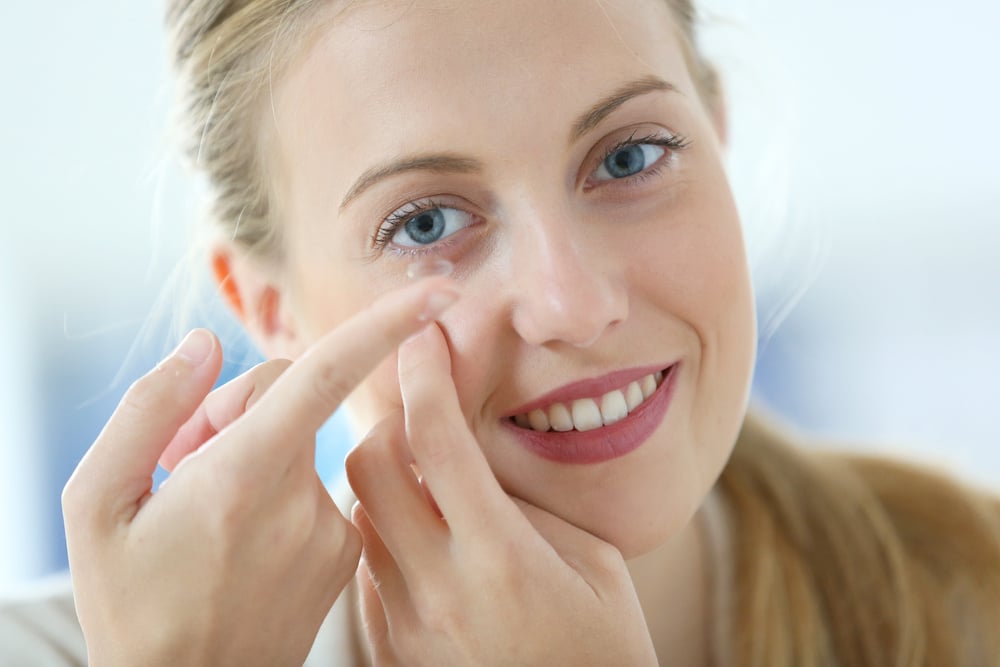 Young woman putting eye contact lense on